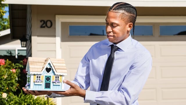 person holding a small model of a house