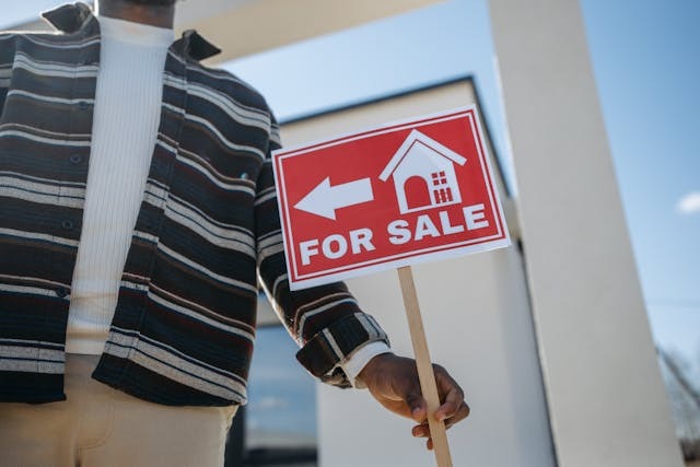 person holding a for sale sign