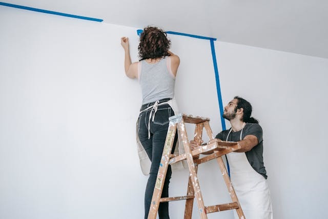 two people puttinhg tape on walls