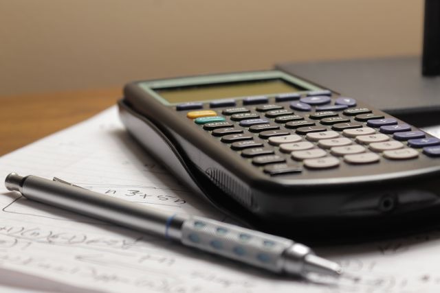 A calculator next to a pen
