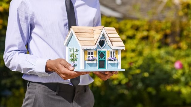 person holding a figure of a house