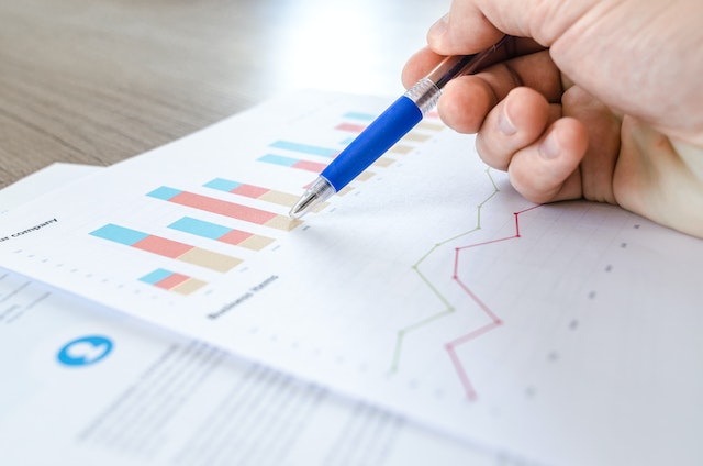 a blue pen pointing to a section of a line graph on a piece of paper