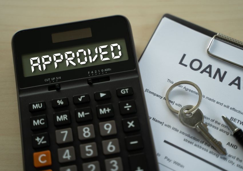 a calculator with the word approved on it next to a mortgage loan