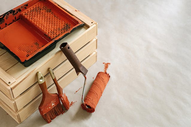 a couple of paint rollers next to a tray of orange paint