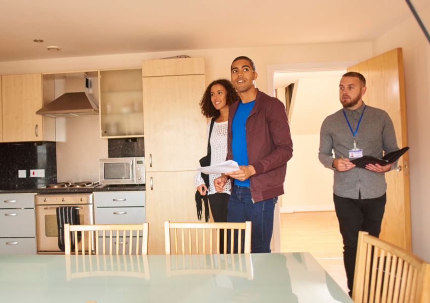 a couple of tenants taking a tour of a rental property with property managers in the background