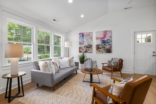 a living room with a grey couch and two brown leather chairs