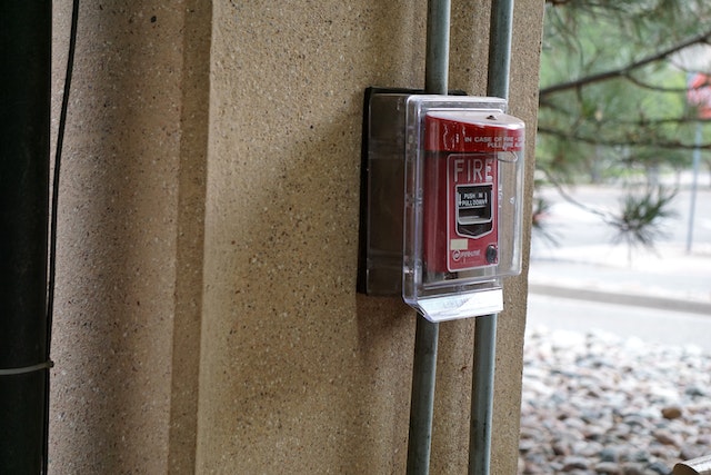 a red fire alarm system in a clear plastic cover
