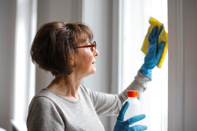 a tenant using cleaning gloves and products to clean the window