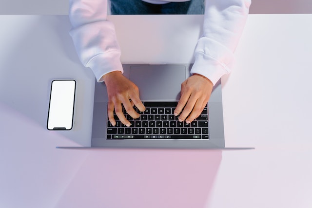 birds eye view of someone typing on a laptop at a white desk