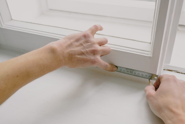 contractor using a ruler to note down measurements on a window