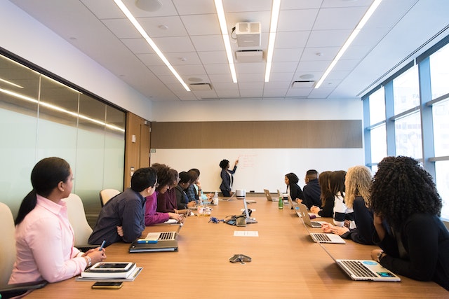 employees sitting around a conference table looking at a presenter