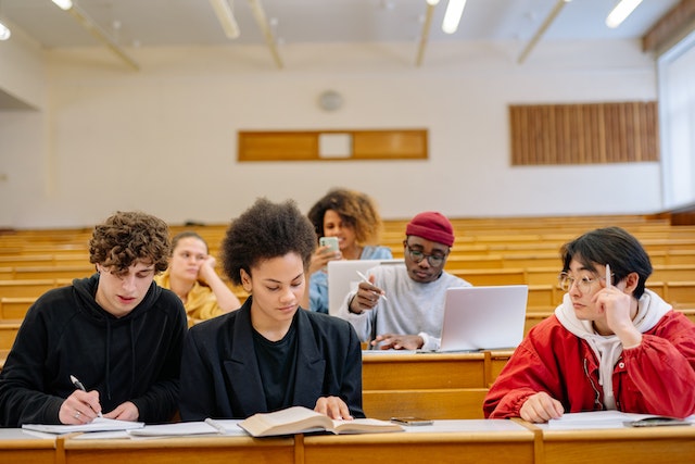 group of students in a lecture hall taking notes and looking at textbooks