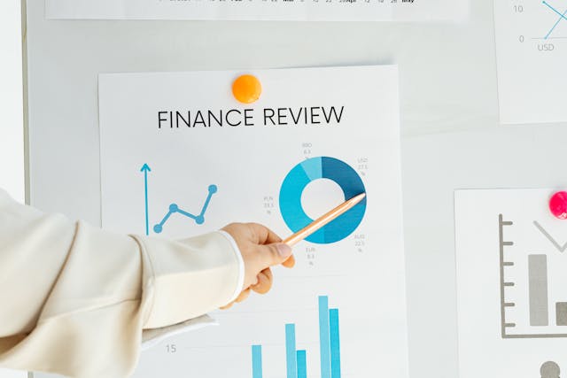 hand pointing to a financial review document showing different graphs