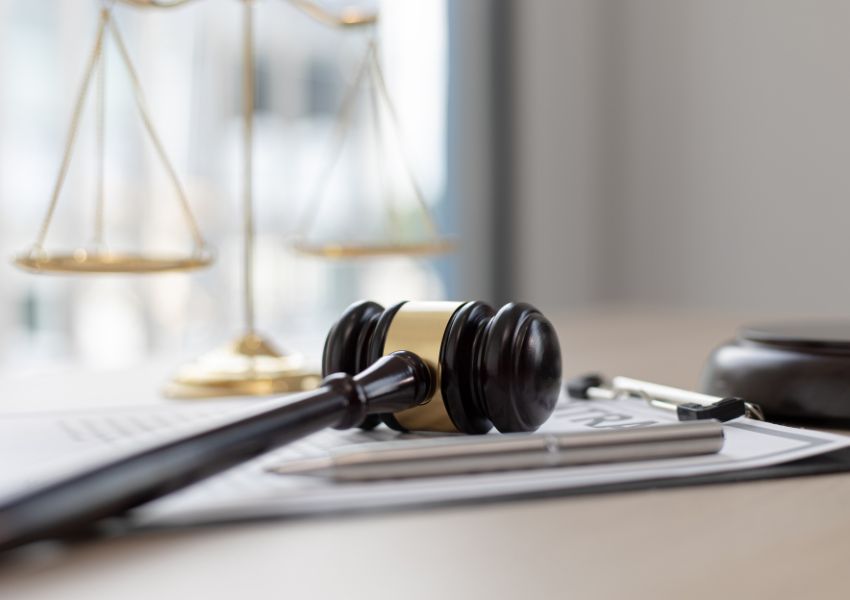 judges gavel on a legal document with a gold balance in the background