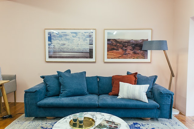 living room with a blue couch and two framed paintings above it