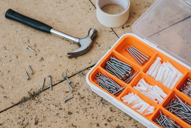 orange toolbox with screws and nails a hammer and tape