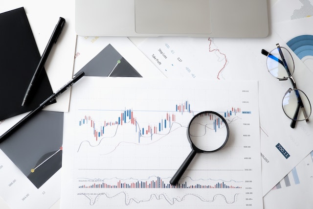 papers with market trends written on them and a magnifying glass to see numbers better