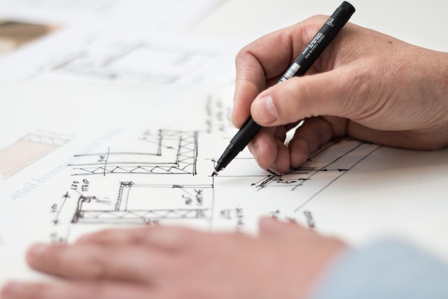 person drawing the layout of a home overtop of the existing blueprint