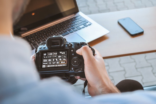 person holding a digital camera while looking at the settings on its screen