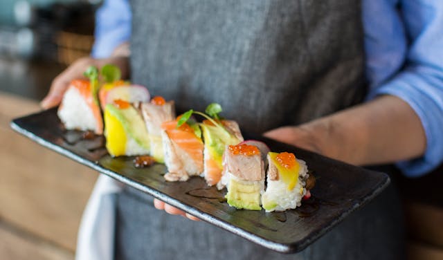 person holding a plate of sushi