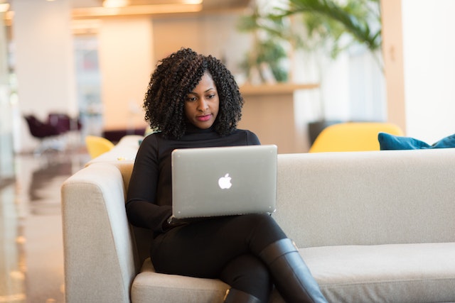 person sitting on a grey couch using a computer