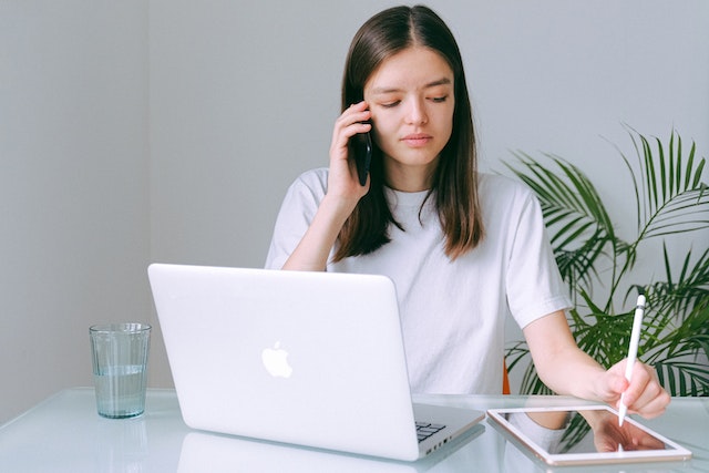 person talking on the phone while taking notes on an iPad