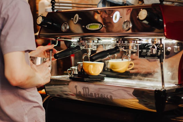 person using a coffee maker to make a cappuccino