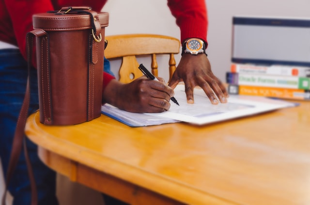 person wearing a red sweater signing a lease agreement