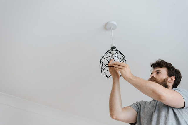 person with a beard changing a lightbulb