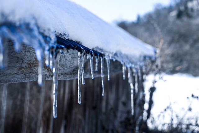Close-up of icicles hanging from a snow-covered roof 