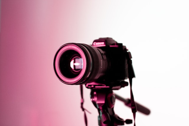 professional camera on a tripod with a pink light in the background