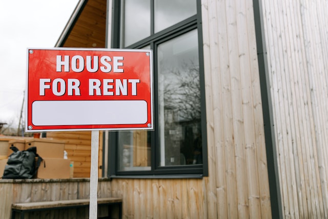 red house for rent sign in the front yard