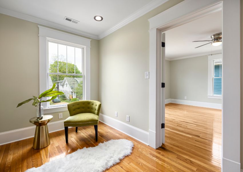 rental property with white walls light wood flooring and a green chair in front of large window