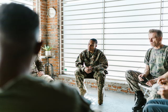 several military personnel sitting in foldout chairs talking