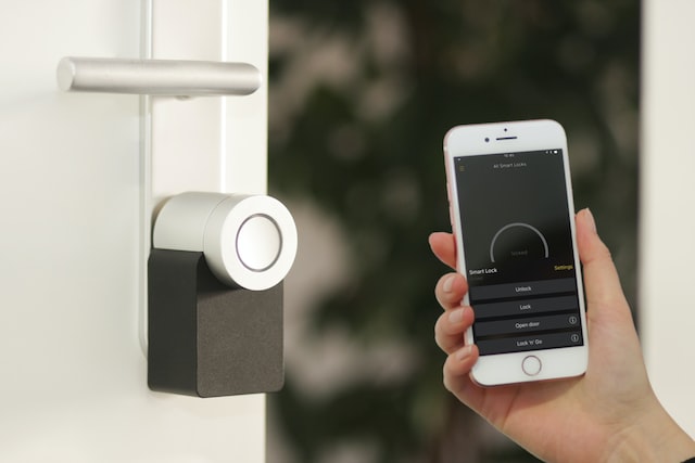 smart lock on a door and someone holding up a phone with online locking systems