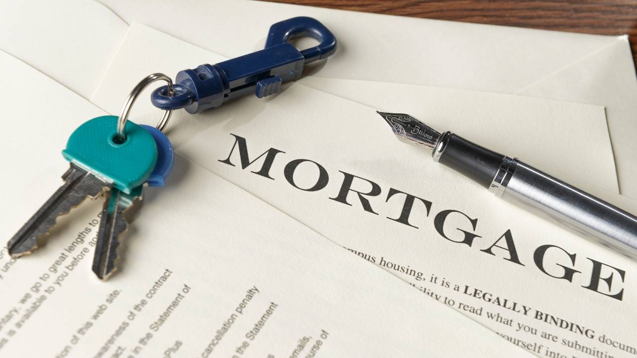 two house keys on top of a mortgage contract with a pen