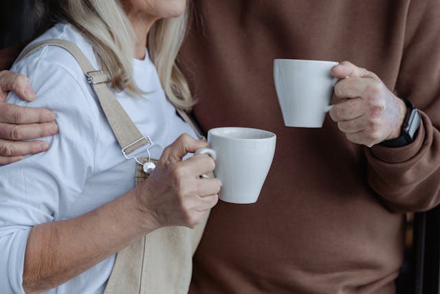 two people holding white coffee mugs