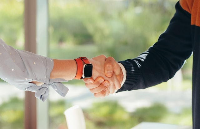 two people shaking hands in front of a large window